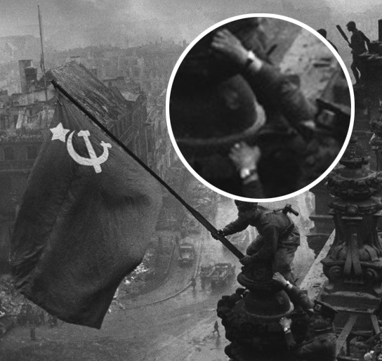 Zdjęcie - symbol - żołnierze zwycięskiej armii czerwonej wieszają flagę na dachu Reichstagu - gdy przyjrzymy się, jeden z triumfujących  żołnierzy ma na ręku "łupy wojenne", oczywiście nam pokazywano zdjęcia bez tych zgrabionych ozdób.